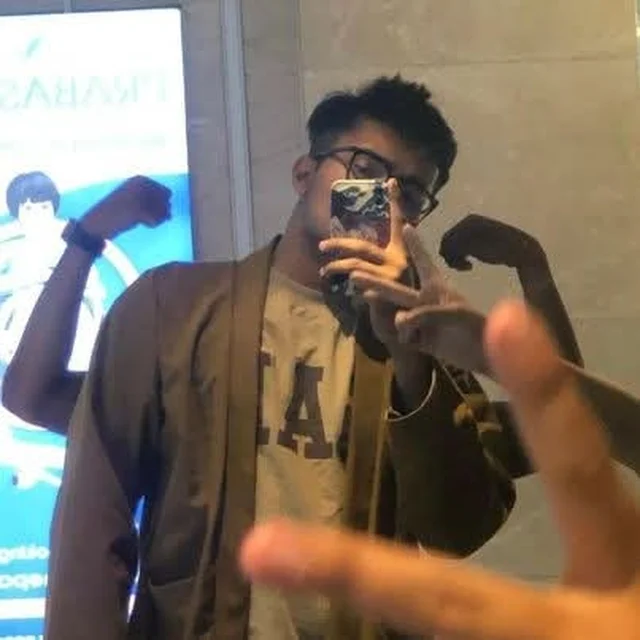 Martin flexing in a mirror selfie while an unidentified hand throws a peace sign in the foreground