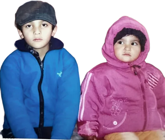 Young Martin in a flat cap looking unimpressed, next to his little sister in a pink hoodie giving side-eye