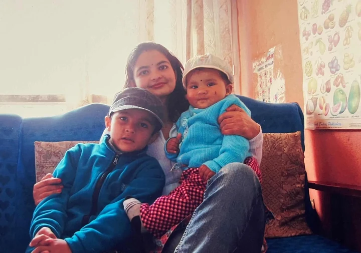 Martin as a baby held by his saili maiju as a young woman, with another young cousin seated beside them on a blue sofa