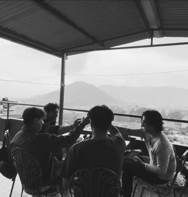 Martin and his friends toasting on a rooftop overlooking Kathmandu hills