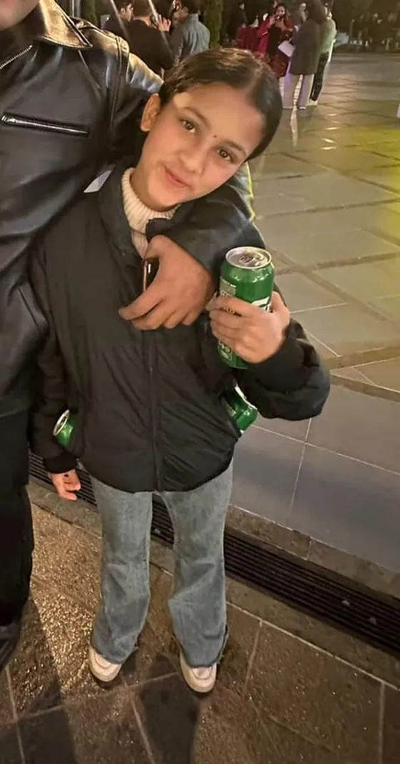 Martin's little sister striking a pose with two soda cans as props